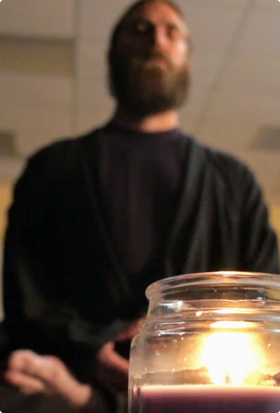 Martial arts practitioner in meditative stillness with candlelight, Denver CO